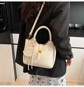 Detail of lychee pattern leather handbag with golden lock and cute dog shaped charm