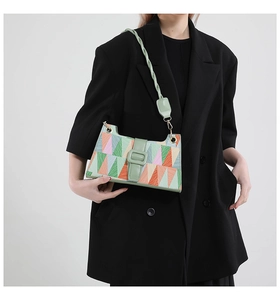 Detail of geometric pattern underarm bag with pastel green twisted strap and buckle