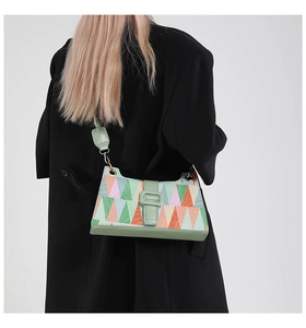 Detail of color-block baguette bag with geometric patterns and green leather shoulder strap