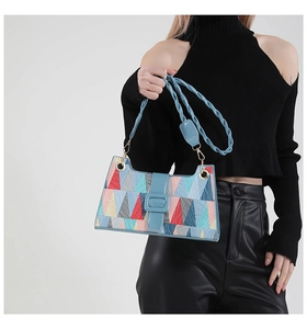 Detail of colorful geometric pattern shoulder bag with blue woven strap and magnetic clasp