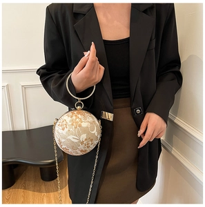 Detail of sphere evening bag featuring white floral lace and crystal gold handle