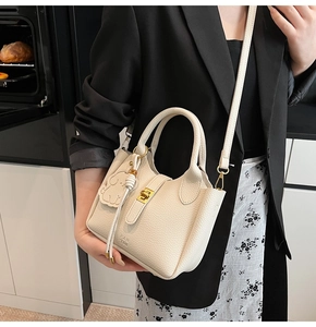 Detail of off-white lychee grain leather bucket bag with gold hardware and charm