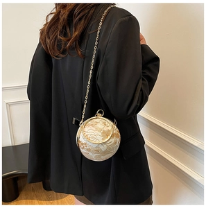 Detail of spherical evening bag featuring white lace overlay and gold chain strap