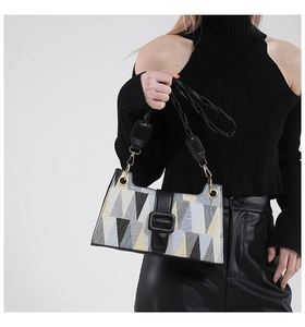 Close-up of geometric pattern handbag with leather strap and square buckle detail