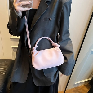 Pink ruched cloud bag with top handle and fashion text logo shown on a model