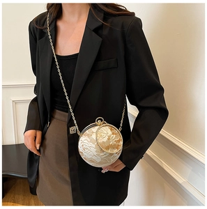 Detail of spherical lace clutch bag with gold metal frame and delicate floral lace overlay