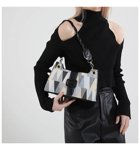 Detail of geometric patchwork shoulder bag with metal rings and woven strap on model