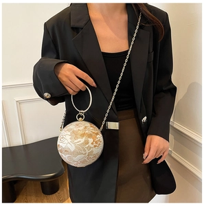 Detail of spherical lace evening bag featuring a rhinestone handle and golden chain strap