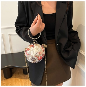 Close-up of spherical evening bag featuring floral embroidery and crystal ring handle