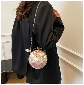 Detail of round floral evening bag with lace patterns and gold ring handle