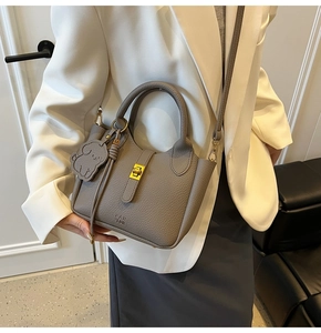 Detailed view of gray lychee leather bucket bag with gold lock and dog charm