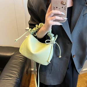 Green pleated handbag with bow detail shown in a stylish mirror selfie setting