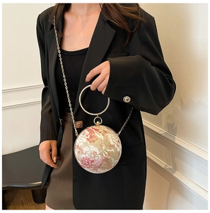 Detail of floral sphere handbag with golden metal ring handle and chain strap on a model
