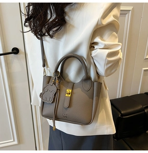 Detailed macro view of litchi texture leather bucket bag with golden twist lock and charm