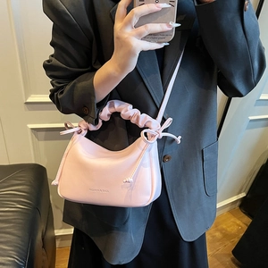 Pink pleated hobo bag with top handle and crossbody strap styled with a grey suit blazer