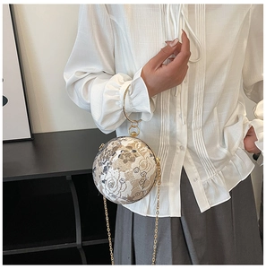Detail of spherical lace evening clutch bag with floral patterns and gold chain strap