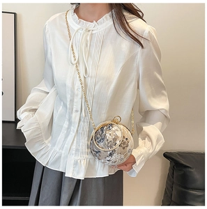 Detail of spherical marble-patterned clutch bag with gold handle and chain strap