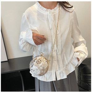 Macro detail of round spherical evening bag with golden floral jacquard and metallic handle