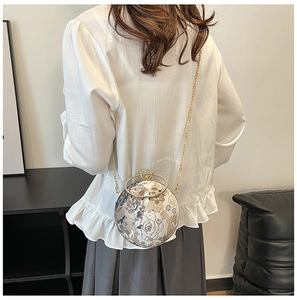 Detailed close-up of spherical evening bag with floral embroidery and gold ring handle