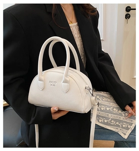 Close-up of white lychee textured boston bag with handles and adjustable shoulder strap