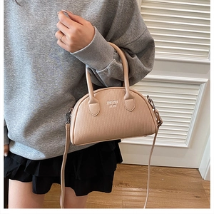 Detail of pink pebbled leather shell bag with handle and detachable shoulder strap