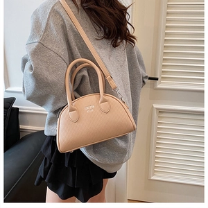 Detail of beige textured shell bag with top handle and detachable shoulder strap