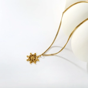Polished 18K gold plated stainless steel rudder pendant necklace on white stand