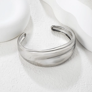 Detail of silver liquid metal wave open bangle with polished finish on white stone