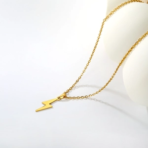 Détail d'un collier doré avec pendentif en forme d'éclair sur un support blanc élégant