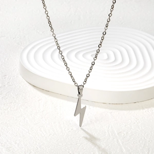 Collier minimaliste avec pendentif éclair argenté sur un support géométrique