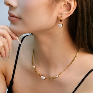 Elegant gold-plated heart pearl necklace and earring set shown on a female model