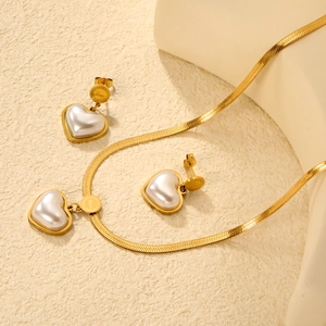 Golden heart pearl jewelry set with snake chain and Love engraved discs on sand