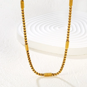 Polished gold stainless steel cuban chain necklace displayed on a white textured stand