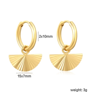 Vue macro de boucles d'oreilles créoles dorées en acier avec pendentifs plissés