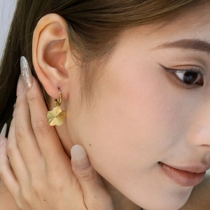 Gros plan de boucles d'oreilles fleuries en or 18 carats sur l'oreille d'un mannequin
