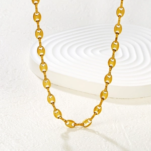 Minimalist 18K gold coffee bean link necklace displayed on white geometric props