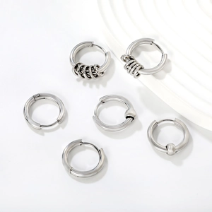 Trois paires de boucles d'oreilles créoles en acier inoxydable argenté sur plateau blanc poli