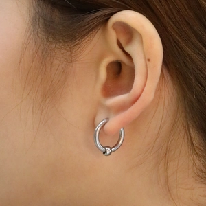 Macro d'une boucle d'oreille anneau à bille captive en argent portée sur le lobe