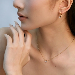 Elegant gold jewelry set featuring a round white diamond pendant necklace and earrings