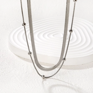 Minimalist double layer silver necklace featuring a flat blade chain and beaded detail