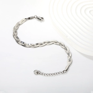 Macro detail of braided stainless steel snake chain bracelet with lobster clasp and tag