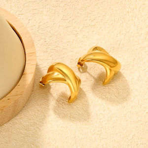 Détail de boucles d'oreilles dorées torsadées en forme de C avec finition brillante