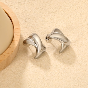 Détail macro de boucles d'oreilles argentées en forme de X avec finition polie brillante