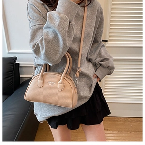 Detailed view of beige shell handbag with wave texture and adjustable shoulder strap