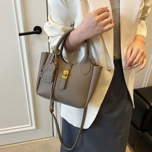 Minimalist pebbled leather bucket bag in taupe with gold buckle and dog charm