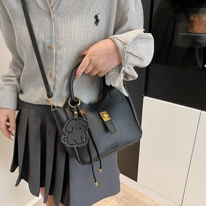 Elegant black lychee leather bucket bag with gold twist lock and dog charm