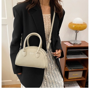 Detail of off-white shell bag with vertical embossing and adjustable shoulder strap