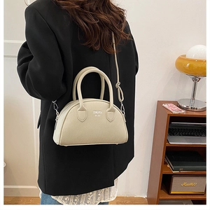 Detailed view of woven texture crossbody bag with adjustable strap in warm home setting