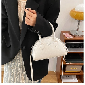 Detail of white shell handbag with lychee texture and adjustable strap in home setting