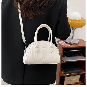 Detailed view of white pleated boston bag with logo embossing and metal base studs